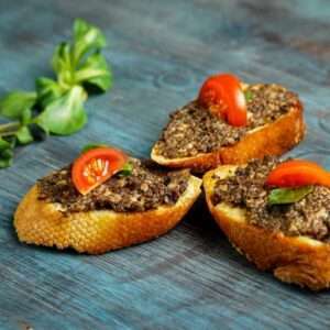 tapenade on bread with tomatoes and basil
